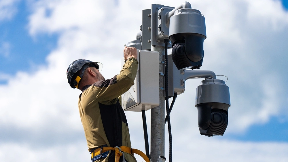 Technician performing maintenance on mounted surveillance cameras, representing Ecamsecurity’s commitment to reliable security solutions
