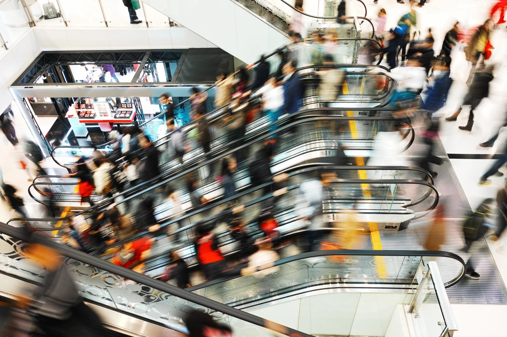 Ecamsecurity Surveillance Solutions for Retail Centers and Crowd Management Busy retail center with escalators and shoppers, suitable for Ecamsecurity’s crowd monitoring and security solutions.